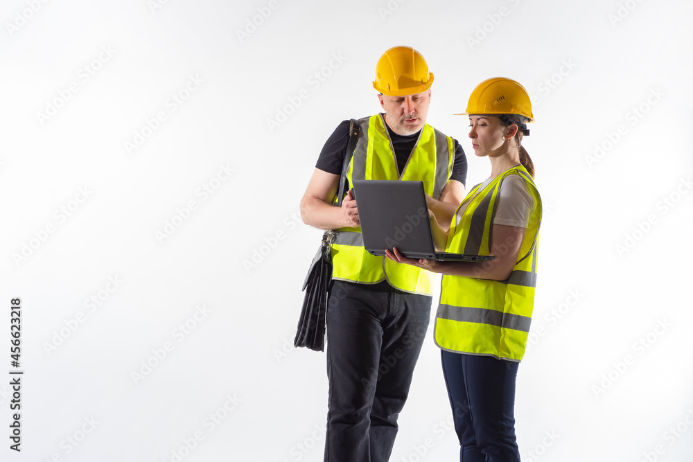 Builders meeting. Two builders on white background. Builders in yellow vests and helmets. Construction company employees. Laptop in hands engineers. Meeting of two engineers. Construction inspectors Builders meeting. Two builders on white background. Builders in yellow vests and helmets. Construction company employees. Laptop in hands engineers. Meeting of two engineers. Construction inspectors