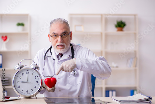 Old male doctor in time management concept