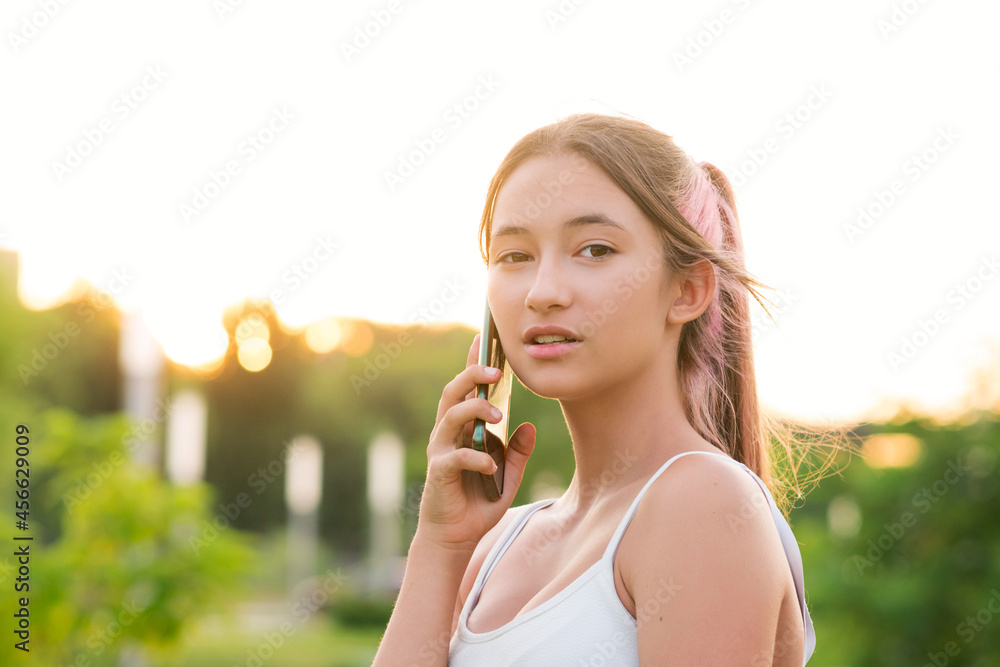 Girl teenager uses Smartphone to talk. Candid portrait teen with cellphone in real life