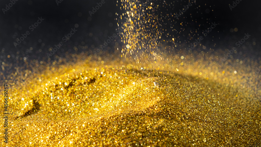 Sprinkle glittering gold powder elegant and precious on a black background Sprinkle glittering gold powder elegant and precious on a black background