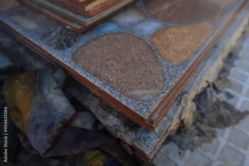 In this photo, piles of hammer pattern ceramic tiles are placed in a special, uneven system. The tiles have a light brown base for dark brown and bluish-gray stones interspersed in some of the tiles. In this photo, piles of hammer pattern ceramic tiles are placed in a special, uneven system. The tiles have a light brown base for dark brown and bluish-gray stones interspersed in some of the tiles.