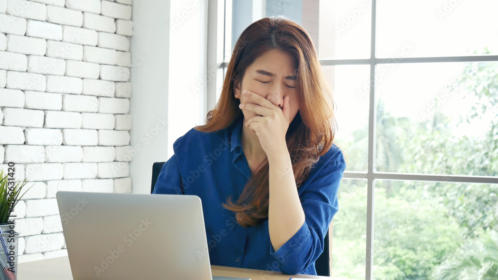 Woman streching arm raised sitting incorrect position home office desk. Back side of young asian woman tired from work body stress back pain office syndrome. Female work from home new normal concept Woman streching arm raised sitting incorrect position home office desk. Back side of young asian woman tired from work body stress back pain office syndrome. Female work from home new normal concept