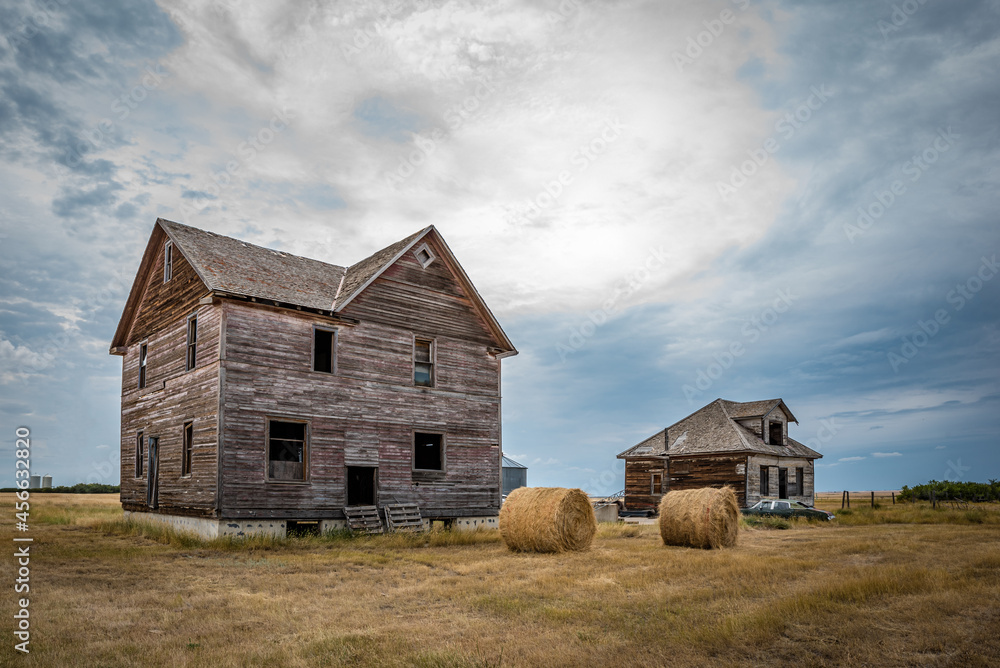 Two abandoned homes, hay bales and a classic car in the ghost town of Robsart, Saskatchewan Two abandoned homes, hay bales and a classic car in the ghost town of Robsart, Saskatchewan