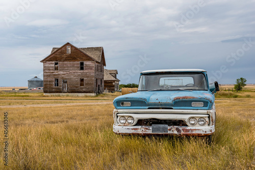 A blue and white classic pick up truck and abandoned home in the ghost town of Robsart, SK 