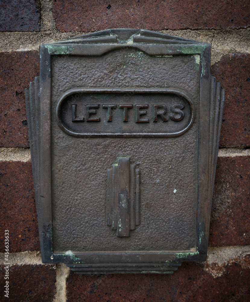 Art Deco letter box set in a dark red brick wall. Art Deco letter box set in a dark red brick wall.