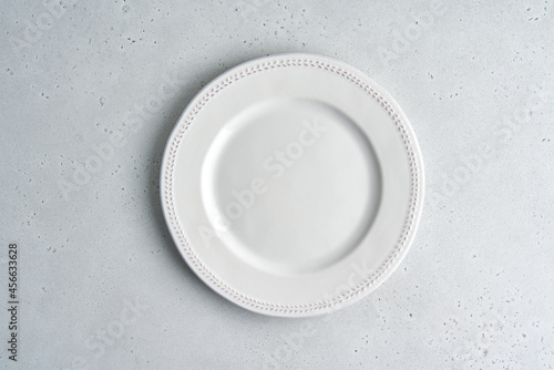 Empty white ceramic plate on light background. Clean tableware. Serving preparation. Novody, Above dishware. Cutlery set. Copy space, top view, horizontal, closeup
