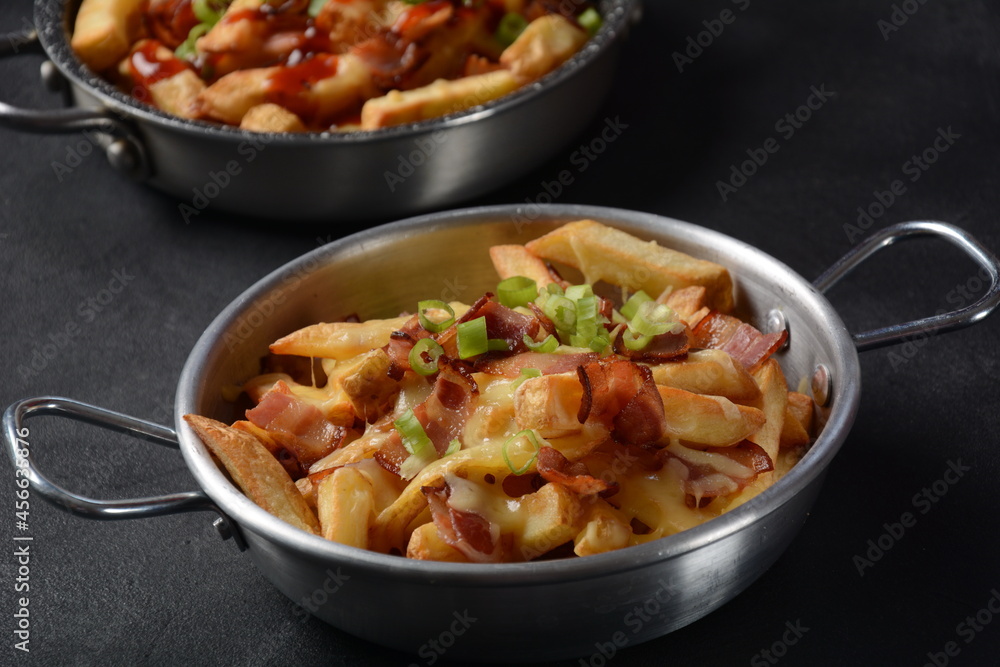 French fries with Melted Cheddar Cheese with Crispy Bacon. Poutine with cheese, bacon and green onions