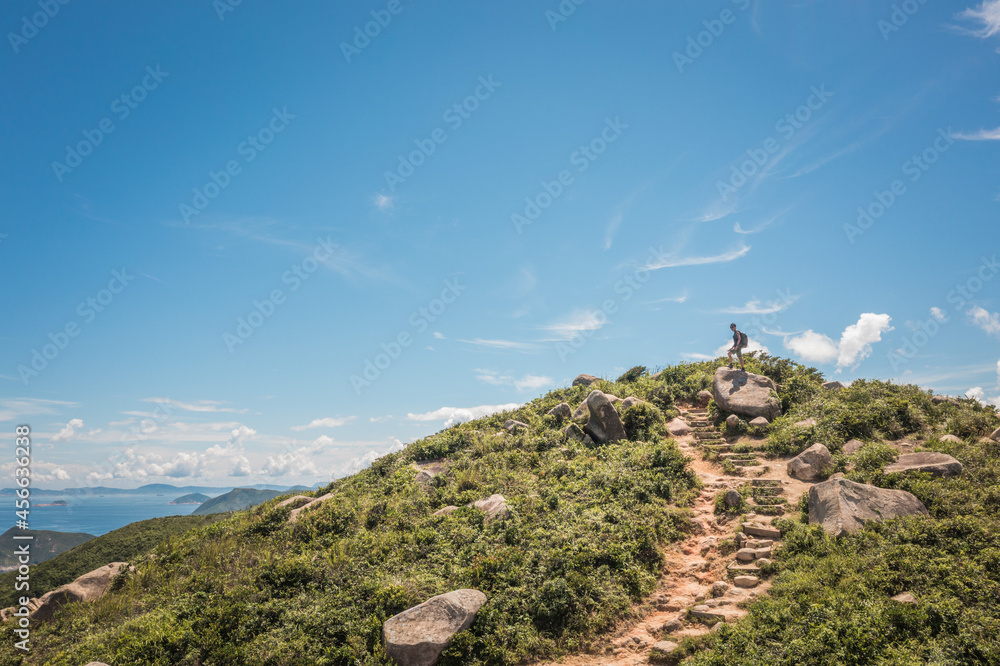 hiking man standing on the peak of a small hill. goal and sucess