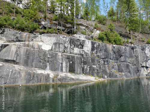 View from the water on the slope of the flooded Marble Canyon  where trees grow  in the Ruskeala Mountain Park on a sunny summer day.