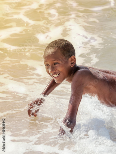 Afro boy playing at the beach, ten years old, rough water    photo