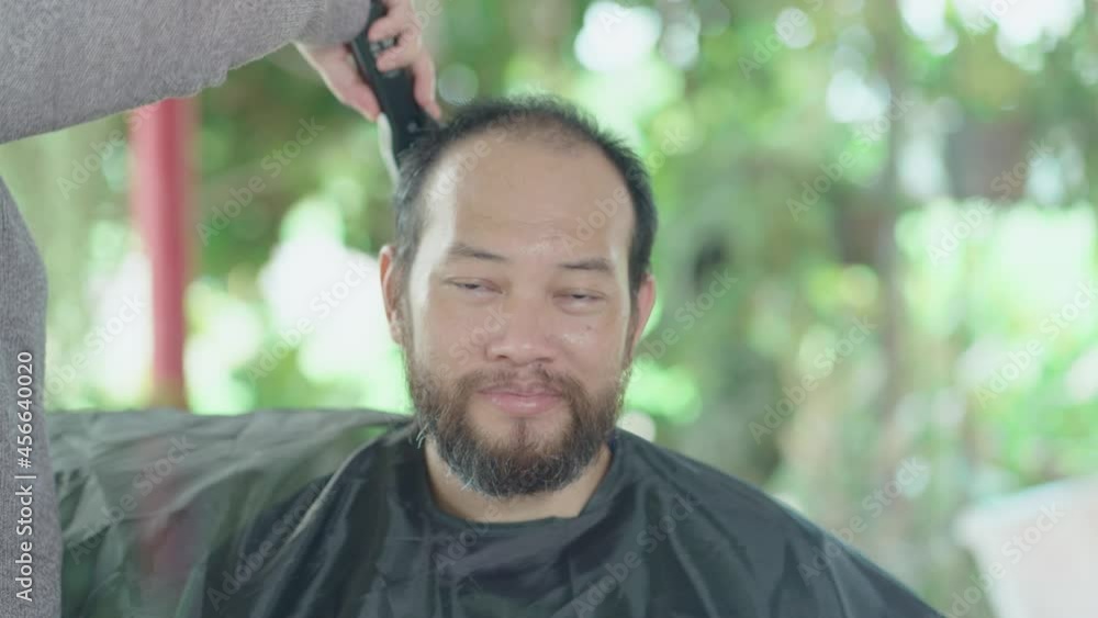 Woman cutting hair to his husband by himself at home with a hair clipper. Asian family stay home and live during lockdown Woman cutting hair to his husband by himself at home with a hair clipper. Asian family stay home and live during lockdown