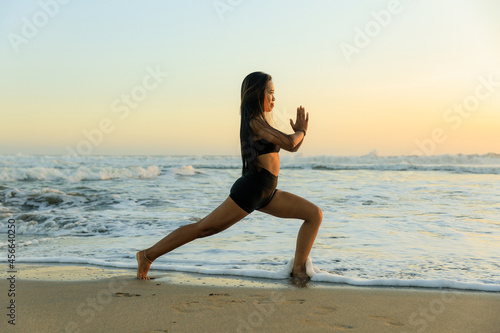 Yoga on the beach. Ashta chandrasana. High lunge pose lengthens the sides of the body, opens hips. Hands in namaste mudra. Healthy lifestyle. Yoga retreat. Copy space. Seminyak beach, Bali