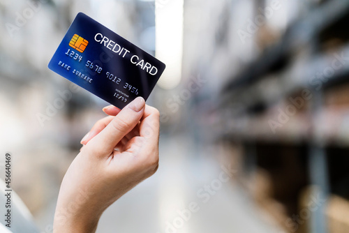 female hand holding credit card on warehouse background.Credit card instead of cash payment concept. Plastic bank card mock up template business ideas concept