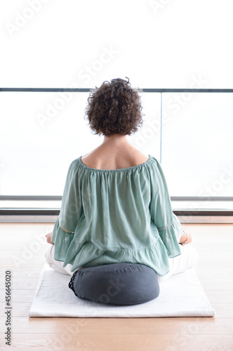 Caucasian woman with short curly hair sited in a yoga lotus pose photo