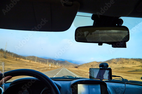 Siberia Baikal, Russia - November 20, 2020: View from of car interior from side of driver to the road and autumn yellow nature landscape with hills through the windshield © keleny