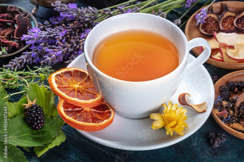 Organic tea. Herbs, flowers and fruit around a cup of tea, on a dark rustic wooden background