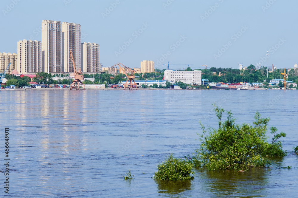 View of the Heihe river port during the flood. Flooded treetops. View of China from the city of Blagoveshchensk, Russia.