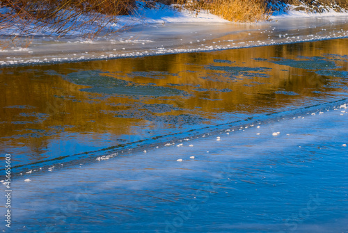 closeup frozen river flow through a forest, winter natural background © Yuriy Kulik