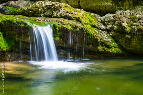 small waterfall on mountain river rushing through canyon