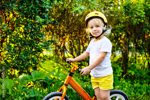 Small children girl with helmets and balance bike outdoors playing