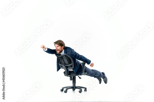 Cheerful business man in a suit is rolling in an office manager chair