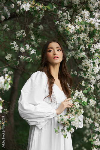 Foto Portrait of a woman in the branches of a blooming apple tree