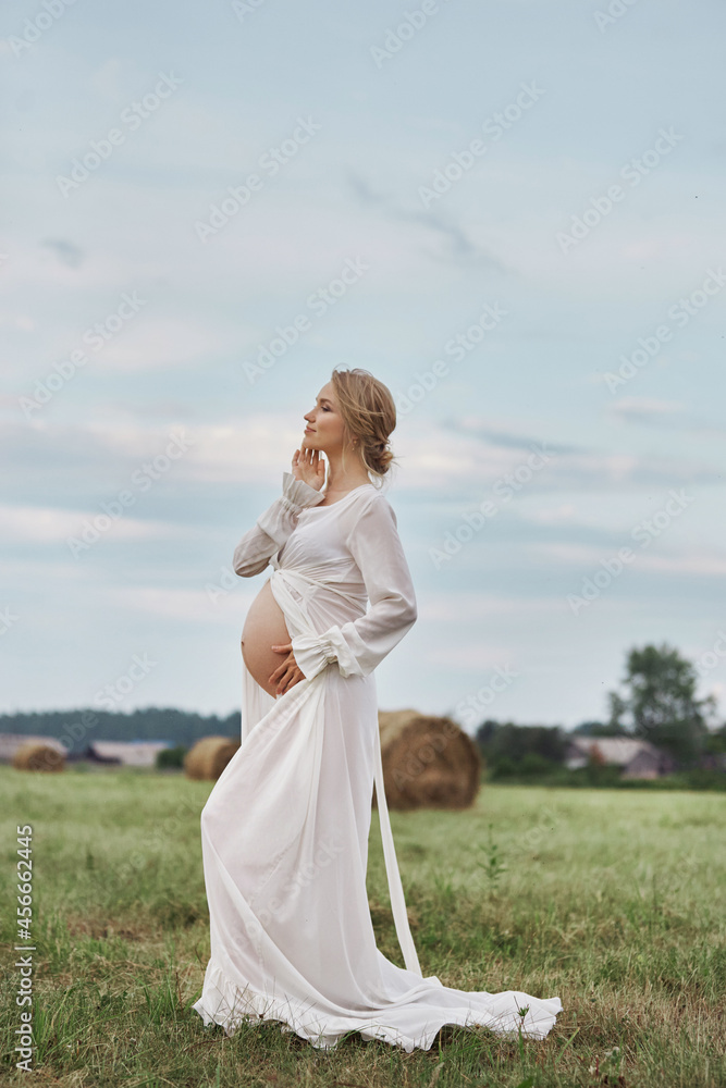Pregnant woman at 9 months of pregnancy walks in summer in field in village, few days before the birth of the child Pregnant woman at 9 months of pregnancy walks in summer in field in village, few days before the birth of the child