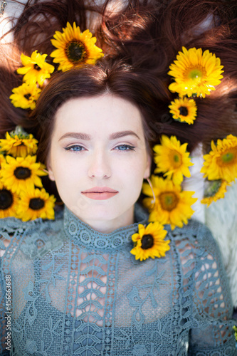 White young girl with dark hair and blue eyes lying portrait within sunflowers