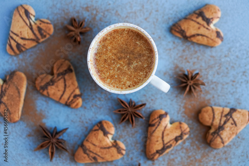 Flatlay of cup of coffee spiced with cinnamon near brown cookies and star anise