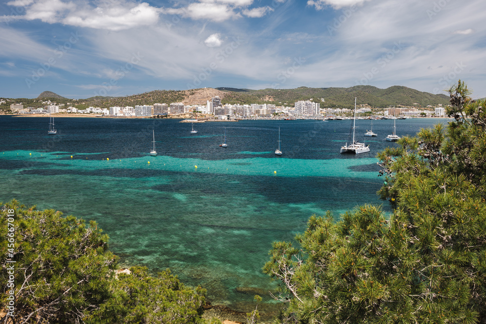 Naklejka premium Bay of Ibiza coastline with turquoise water and yachts on sunny summer day. View to the Port de Sant Antoni de Portmany