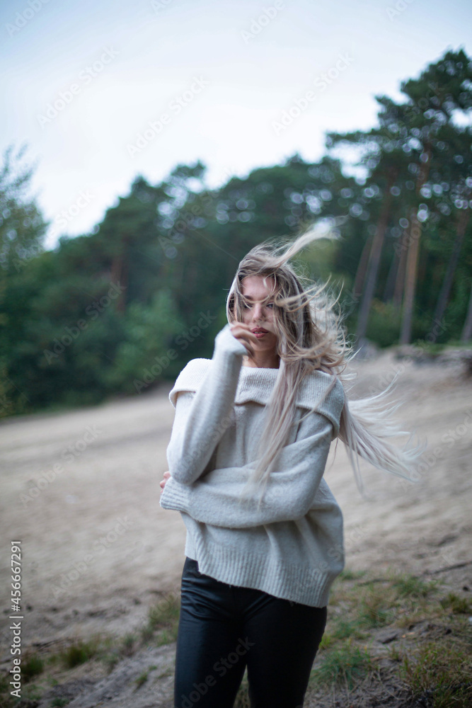 Young white woman with long hair with trees behind windy weather