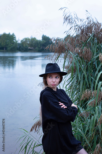 White young woman in dark clothes with lake behind