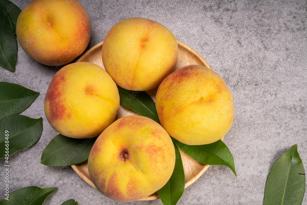 Golden Yellow Peach in wooden plate on gray background. Golden Yellow Peach in wooden plate on gray background.