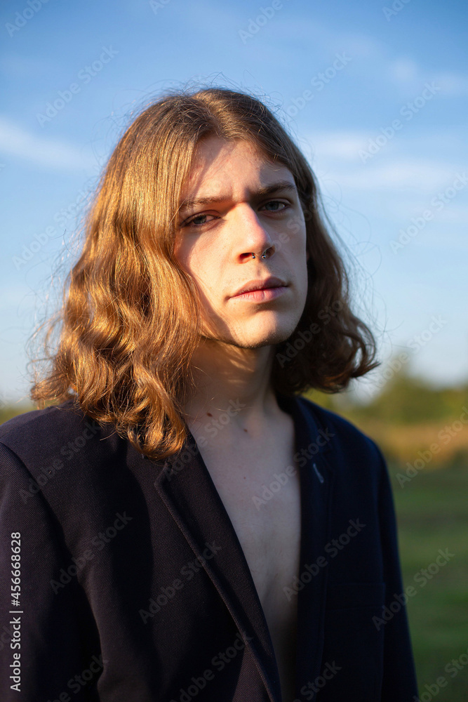 European young white man with long hair with sky behind sunset light European young white man with long hair with sky behind sunset light