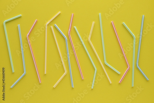 Disposable plastic straws on yellow background.