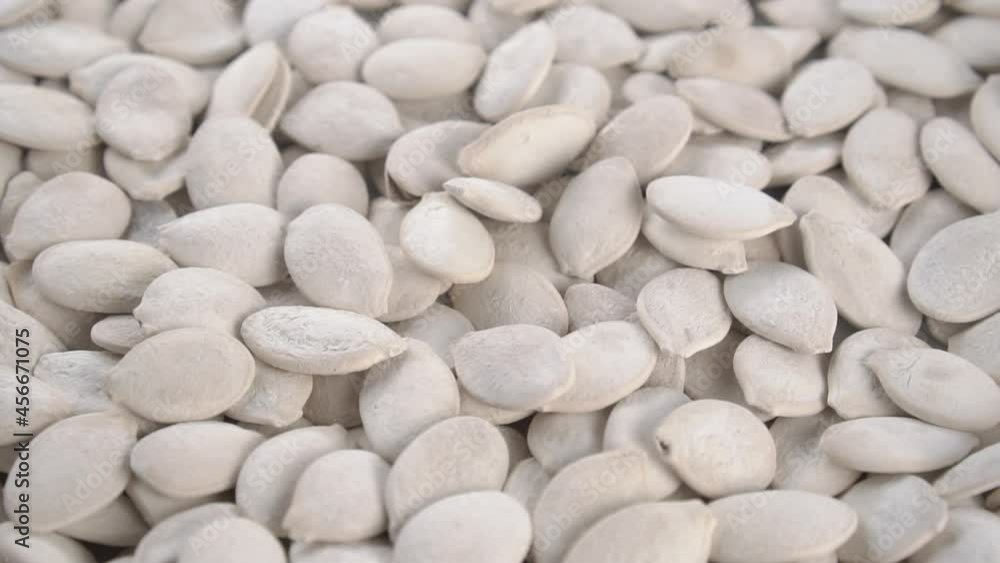 Dried salted unpeeled pumpkin seeds with shells fall into a heap in slow motion. Close up. Rotation Dried salted unpeeled pumpkin seeds with shells fall into a heap in slow motion. Close up. Rotation
