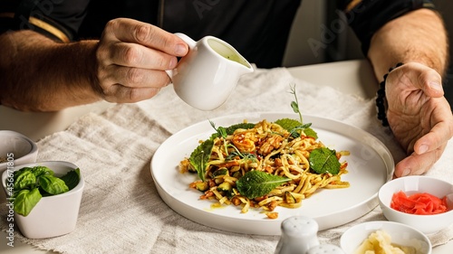 Spaghetti with seafood. The hands of the head chef prepares a traditional pasta with seafood. The cook pours the sauce over the dish. Restaurant serving dish. Mediterranean Kitchen Banner