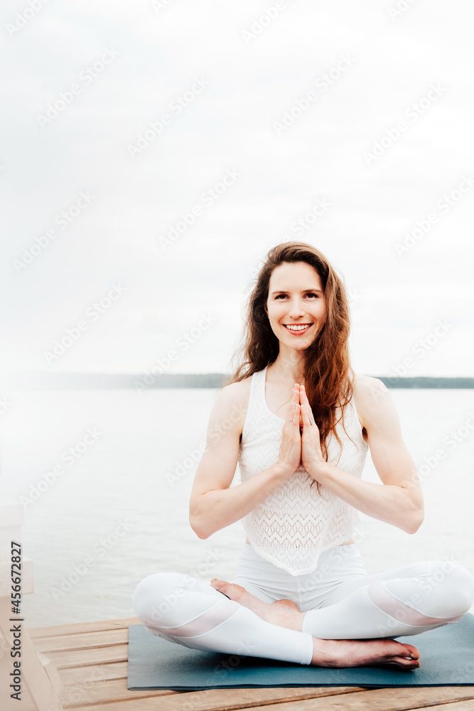 Portrait of beautiful Caucasian woman in white clothes practising yoga on a lake shore Portrait of beautiful Caucasian woman in white clothes practising yoga on a lake shore