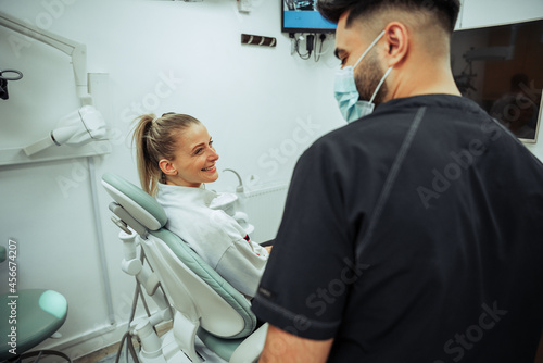 Caucasian female client sitting on doctors bed while engaging in consultation with male nurse