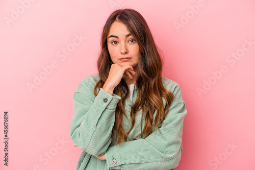 Young caucasian woman isolated on pink background suspicious, uncertain, examining you. © Asier