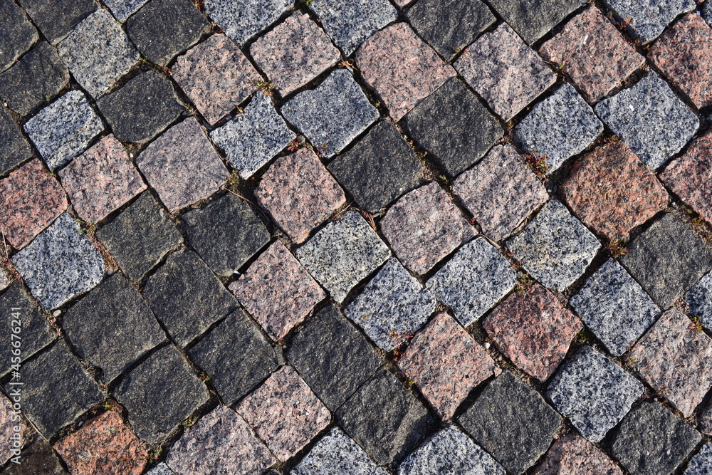 Texture. The sidewalk is lined with granite stones of various colors. 