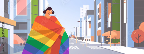 woman with lgbt rainbow flag walking on city street gay lesbian love parade pride festival transgender love concept
