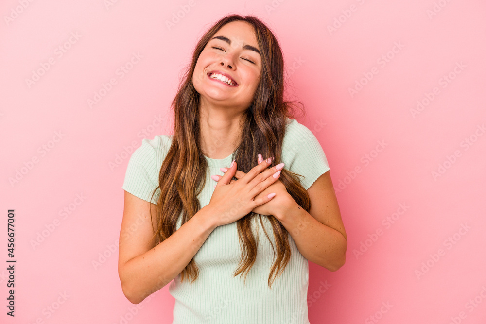 Young caucasian woman isolated on pink background laughing keeping hands on heart, concept of happiness. Young caucasian woman isolated on pink background laughing keeping hands on heart, concept of happiness.