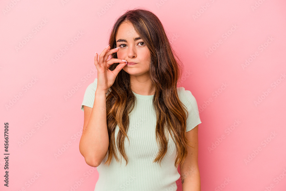Fototapeta premium Young caucasian woman isolated on pink background with fingers on lips keeping a secret.