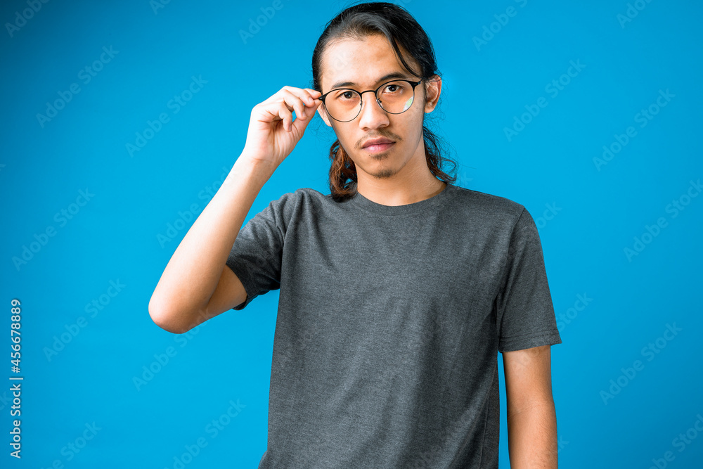 Confident young handsome man smiling while standing against blue background Confident young handsome man smiling while standing against blue background