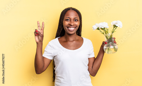 smiling and looking friendly, showing number two or second with hand forward, counting down. decorative flowers concept photo