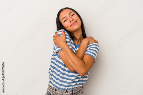 Young latin woman isolated on white background hugs, smiling carefree and happy.