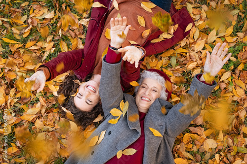 Foto Grandmother and granddaughter lying on foliage and enjoy the autumn