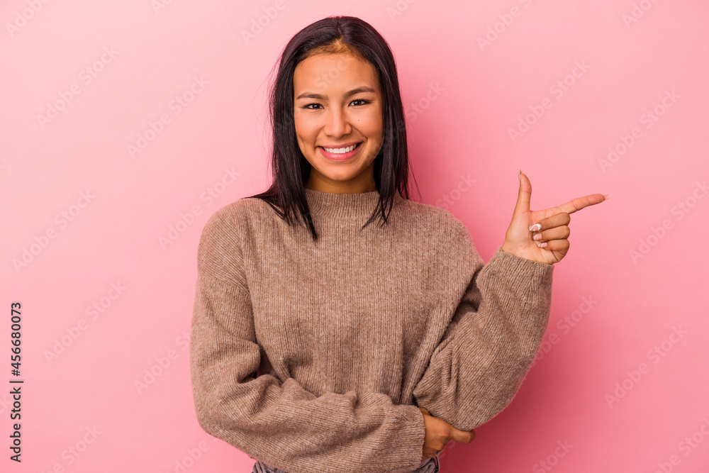 Young latin woman isolated on pink background smiling cheerfully pointing with forefinger away. Young latin woman isolated on pink background smiling cheerfully pointing with forefinger away.