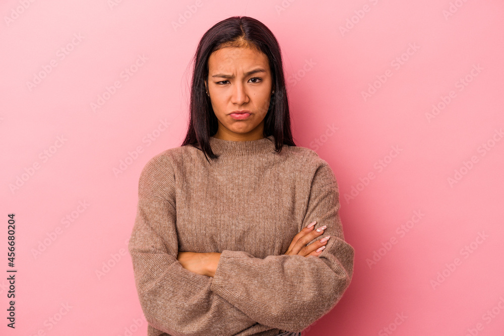Young latin woman isolated on pink background frowning face in displeasure, keeps arms folded. Young latin woman isolated on pink background frowning face in displeasure, keeps arms folded.